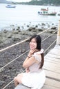 Happiness of asian woman is sitting on wooden bridge Extending into the sea on Holiday. She is smiling in the natural wind and sea Royalty Free Stock Photo